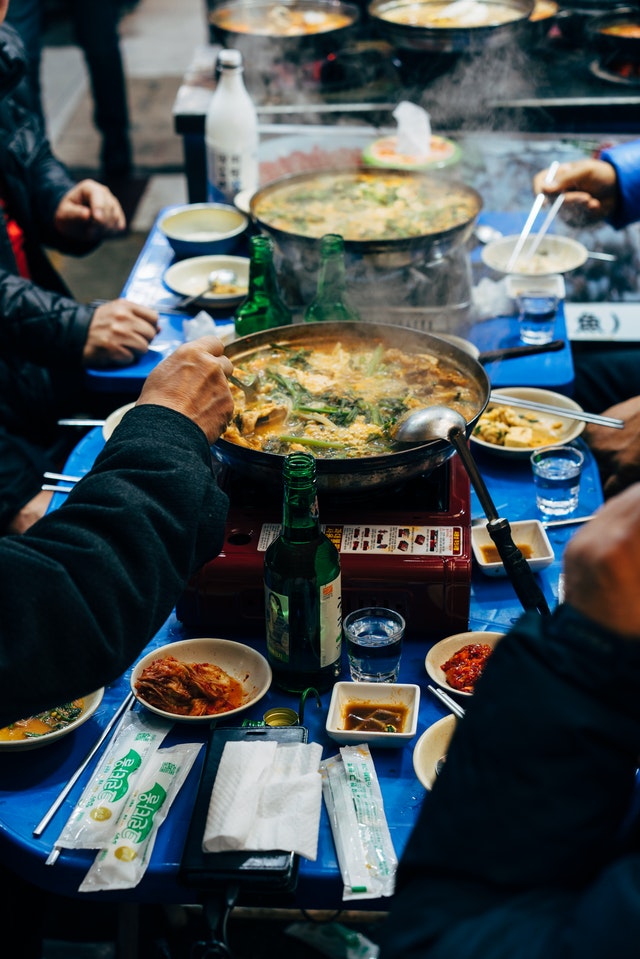 Picture of a family sitting around a hot bowl of curry or soup